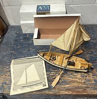 Completed sailboat model on work surface with instruction sheet and boxed kits behind