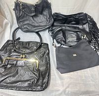 Four handbags laid out: pebbled leather chain shoulder bag, slouch hobo, patent frame bag, nylon shoulder bag