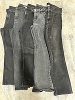 Five pairs of black and grey women’s jeans laid flat showing full length and color variation