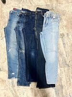 Five pairs of assorted women’s jeans laid side by side revealing various washes, distressing and waistband details