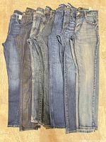 Seven pairs women’s size 30 denim jeans aligned side-by-side