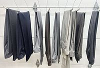 Nine pairs of men’s slacks hanging side-by-side showing full assortment