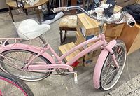 Left side view of the pink Huffy Nassau bicycle showing frame, saddle, rear rack, flat rear tire