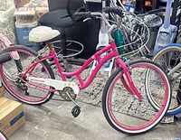 Full left side view showing pink frame, wheels, saddle, chain guard