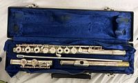 Disassembled Emerson flute showing headjoint, body, footjoint and cleaning rod inside blue-lined case