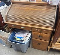 Front view of wood roll-top desk showing tambour cover and right pedestal drawers
