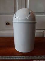 Front view of white Umbra mini waste can with swing lid