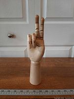 Front view of wooden articulated hand in peace sign pose