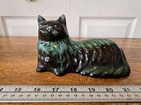 Left-front view of ceramic Persian cat figurine beside ruler