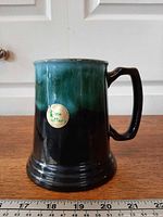 Front view of green-black drip mug with label