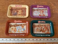 All four trays laid flat showing front graphics and ruler for scale