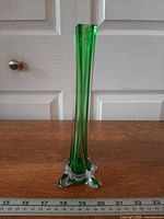 Full side view showing green twisted stem and clear footed base with ruler for scale