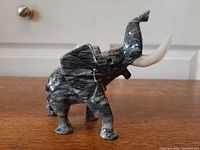 Left side view of stone elephant figurine showing marbled pattern and tusks