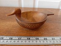 Side view of carved wooden duck bowl showing head, body, tail, pattern, ruler for scale