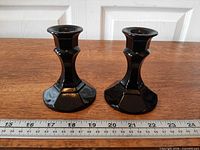 Front view of both black amethyst candle holders beside ruler