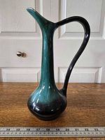 Full view of Blue Mountain Pottery ewer front profile, showing green-to-black glaze and overall form with ruler for scale