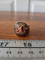 Front view of ring showing raised Maurice Richard image, red enamel background, surrounding text "THE ROCKET"