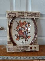 Front view of sealed Gallery Crafts Hummel stitchery kit showing frame and packaged contents