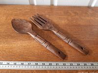 Spoon and fork on wood surface with ruler for scale
