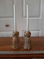 Pair of tassel form candlestick holders with candles, ruler for scale