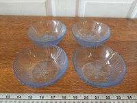 Top view of four light blue glass bowls showing floral pattern and ribs