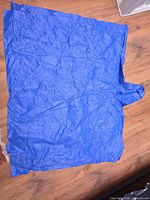Blue rain poncho laid flat showing full size and hood