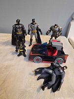 Group shot of five Batman figures and Batmobile on table