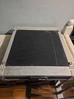 Top view of black plywood panel within aluminum frame