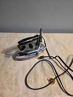 Full view of chrome General Electric dry iron with cord