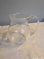 Side view of clear glass pitcher showing frosted leaf pattern and handle