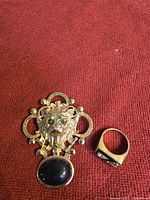 Front view of lion brooch and ring on red fabric