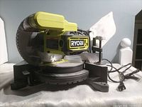 Left side view of Ryobi compound miter saw showing blade guard, miter base and cord