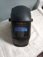Front view of black auto-darkening welding helmet showing lens window