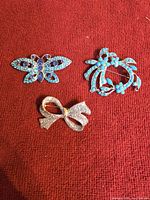 Front view of all three brooches showing stone colors and designs