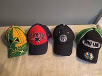 Front view of four caps displaying logos and colors