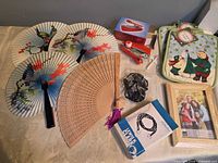All items laid out: paper fans, wooden fan, sewing machine, clothesline cord, potholders, wood frame, straps
