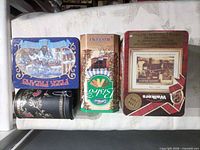 All four metal tins laid side by side showing main graphics