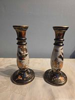 Front view of both porcelain candlesticks showing floral gilt decoration