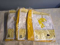 Three sealed yellow rain suits in original plastic packaging