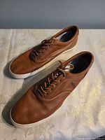 Top and side view of both sneakers showing leather uppers, laces, Polo logo