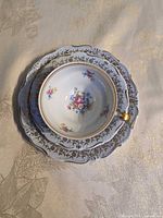 Top view of stacked cup, saucer, plate showing floral centre and gold trim