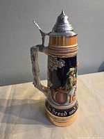Left profile of beer stein showing relief scene and handle