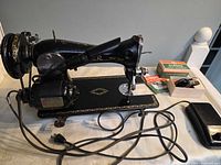 Full view of Singer sewing machine with motor, cords, foot pedal, zigzag attachment box and manual