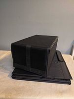 Three folded and one assembled black fabric storage boxes