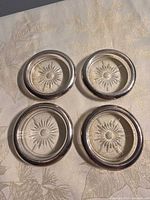 Top view of four coasters showing starburst pattern and silver rims