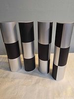 Four silver and black cylindrical tubes standing upright
