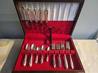Open flatware chest showing knives in lid and assorted spoons and forks in base