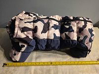 Side view of camouflage puffer dog coat with measuring tape for length reference