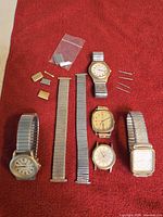 Overview of all watches, loose expansion bracelets, spare pins and end links on red background