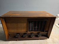 Front view showing cloth grille, glass dial, four knobs